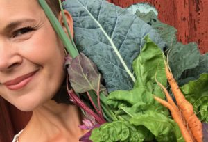 Sara bäckmo tillsammans med ett stort knippe grönsaker i olika färger.