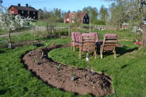 En vårlig bild med grön gräsmatta och en lång böjd upphöjd bädd med bara jord.