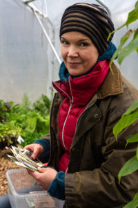 Sara i röd tröja tittar in i kameran i växthuset.