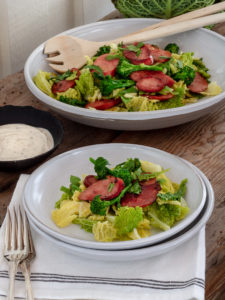 Härlig portion med kål och korv ligger upplagd på ett fat.