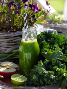 Grönkålsjuice i glaskflaska med randigt sugrör.