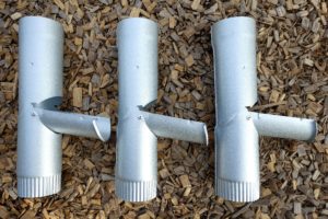 Tre utkastare i zinkfärg ligger på träflis.