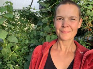 Sara i röd jacka sitter i sitt växthus.