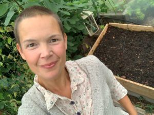 Sara i växthuset vid en pallkrage med frilagd jord.