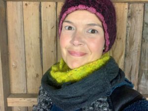 Sara i mössa och stickad halsduk i vedboden.