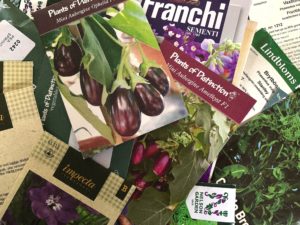 En samling fröpåsar av olika märken i en hög.