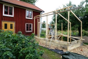 Påbörjat bygge med reglar framför ett hus.
