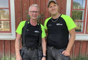 Två byggjobbare står framför ett hus.