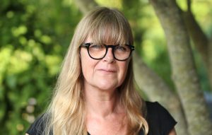 Porträtt av kvinna med långt ljus hår och glasögon.