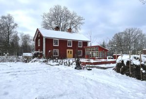 rött hus med massor av snö runtomkring.