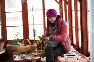 Sara sitter i växthuset och sår.