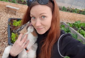 En kvinna med långt hår blir pussad av en valp.