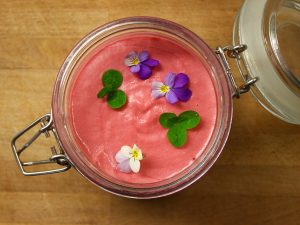 En hallonröd dessert med blommor och klöver serverad i glas.